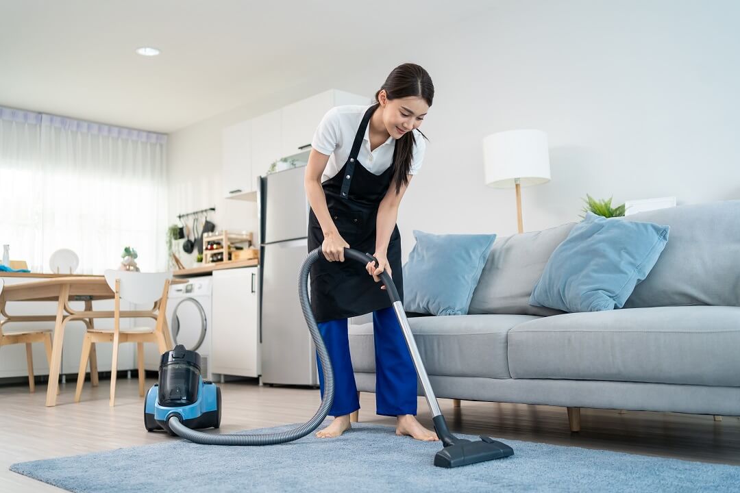 Woman with vacuum cleaning the living room to prevent cockroaches.